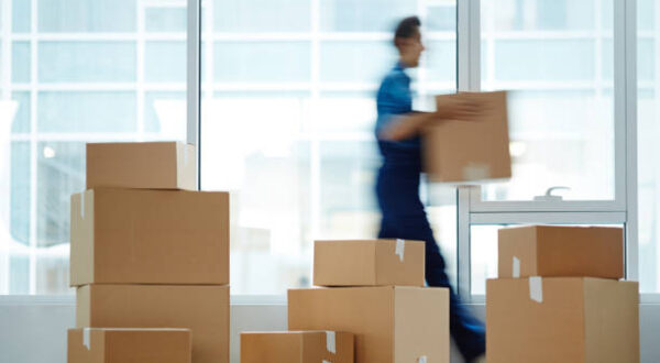 Blurred motion of contemporary worker with packed box walking to new office while delivering it to client